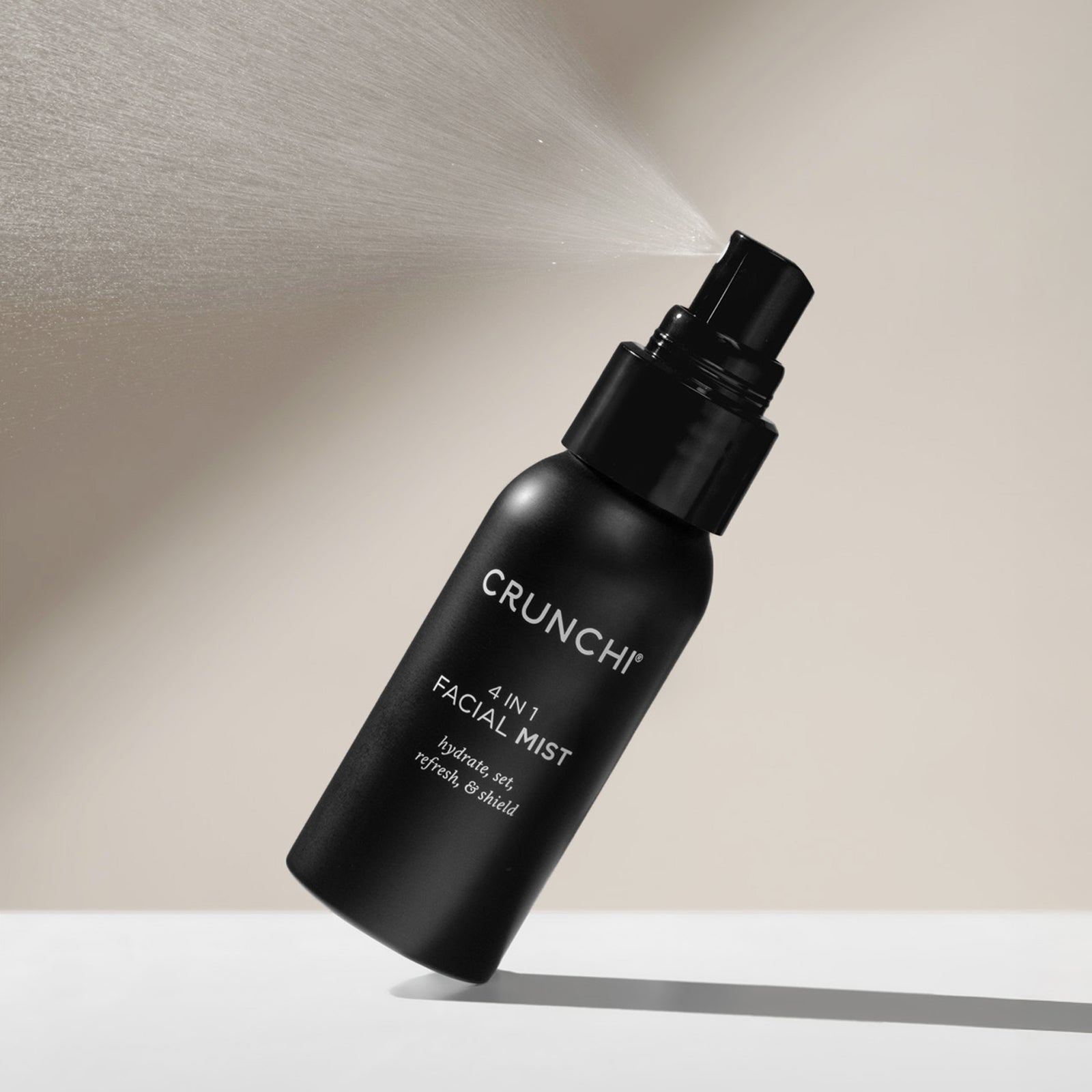 Black Crunchi facial mist bottle being sprayed on a neutral background
