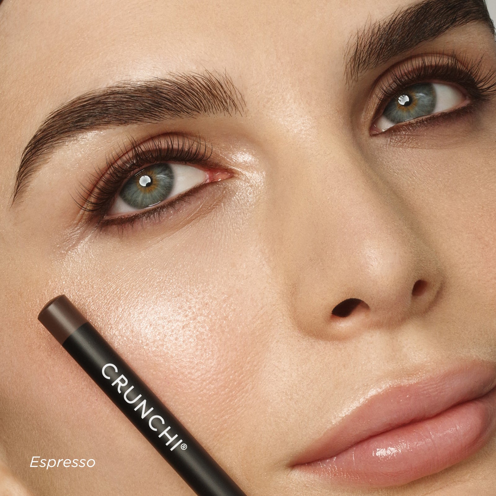 Close-up of a woman's face with a makeup product labeled 'Crunchi Espresso'.