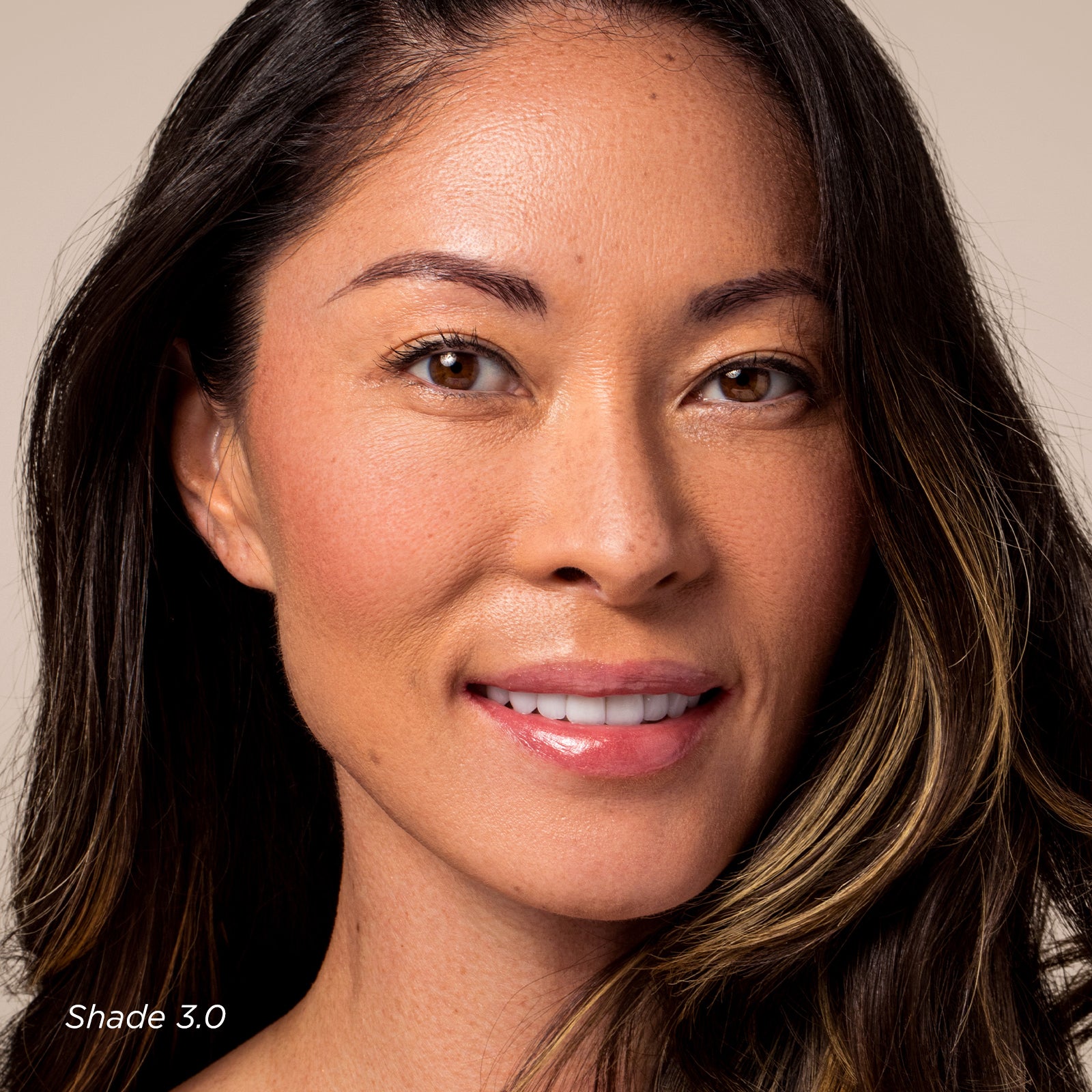 Close-up of a woman with long dark hair against a neutral background