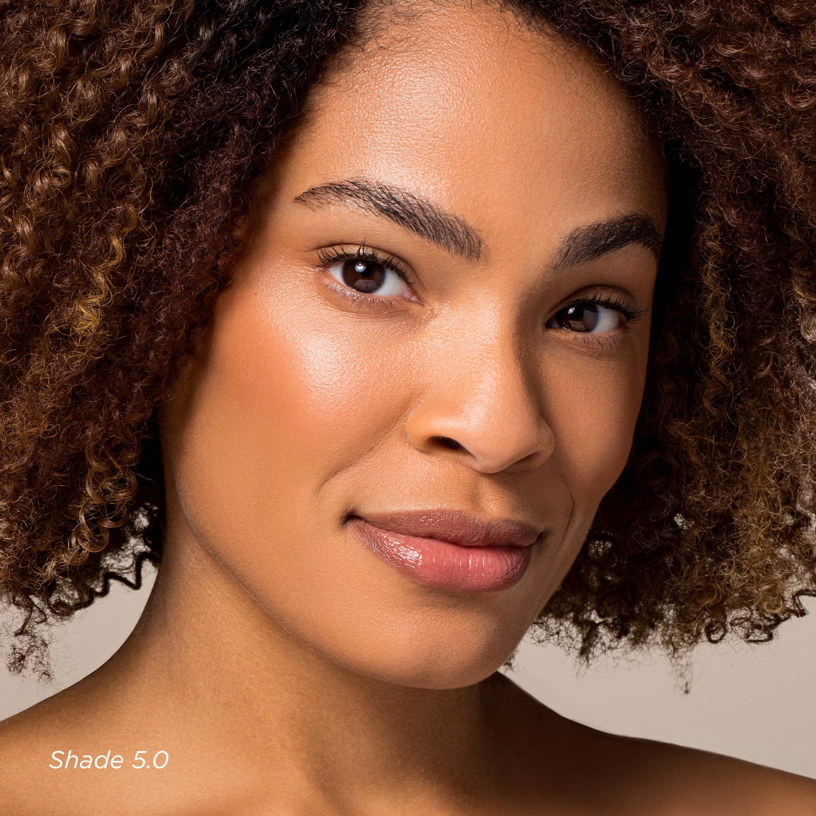 Close-up of a woman with curly hair against a neutral background