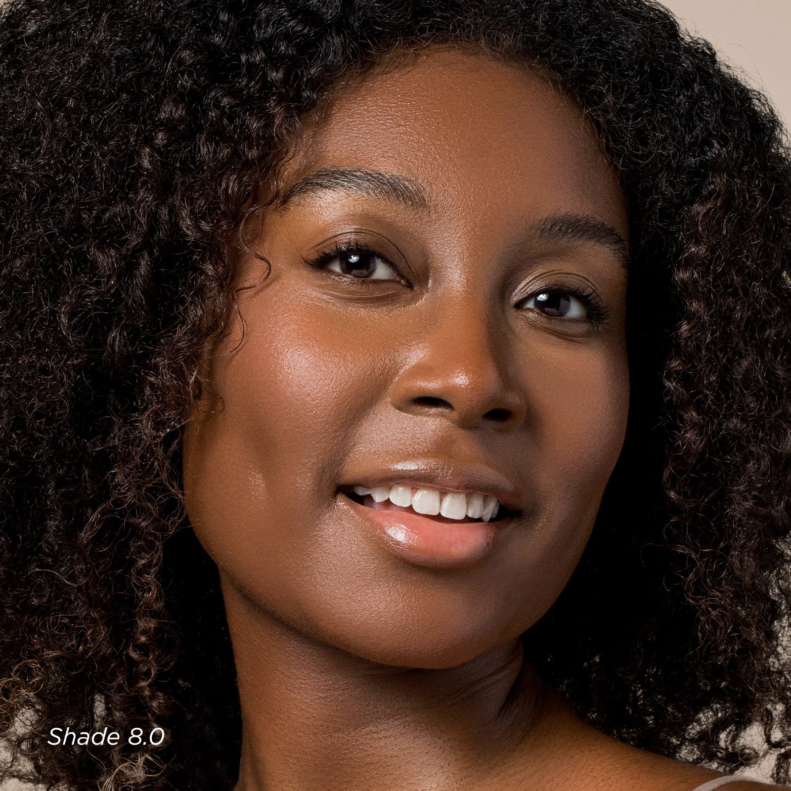 Close-up of a woman with natural hair, wearing a beige top.