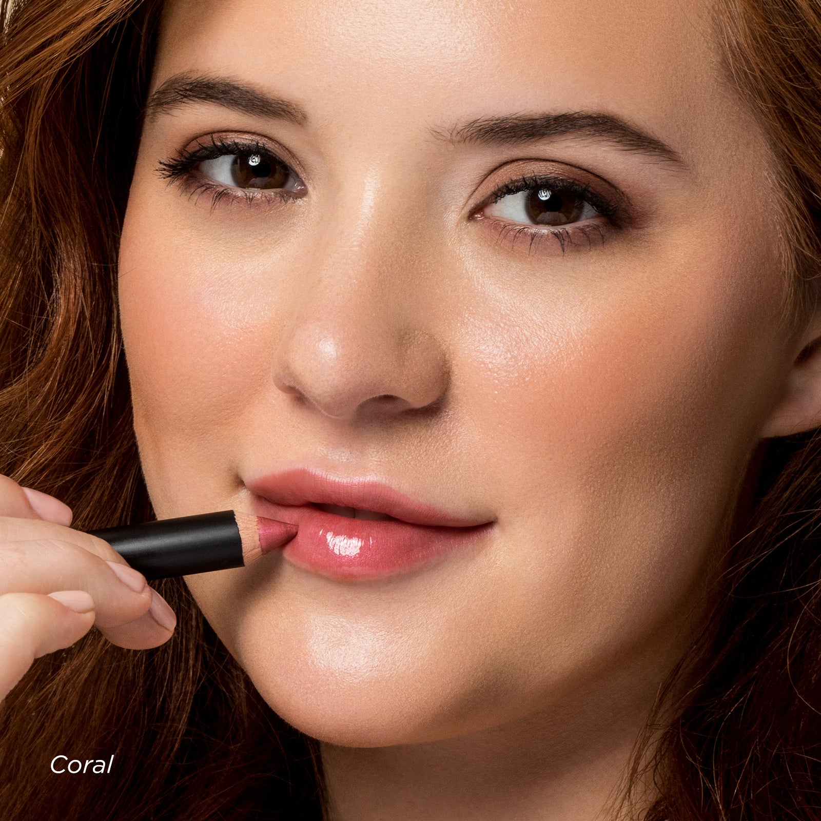 Woman applying coral lipstick with a close-up focus on her lips.