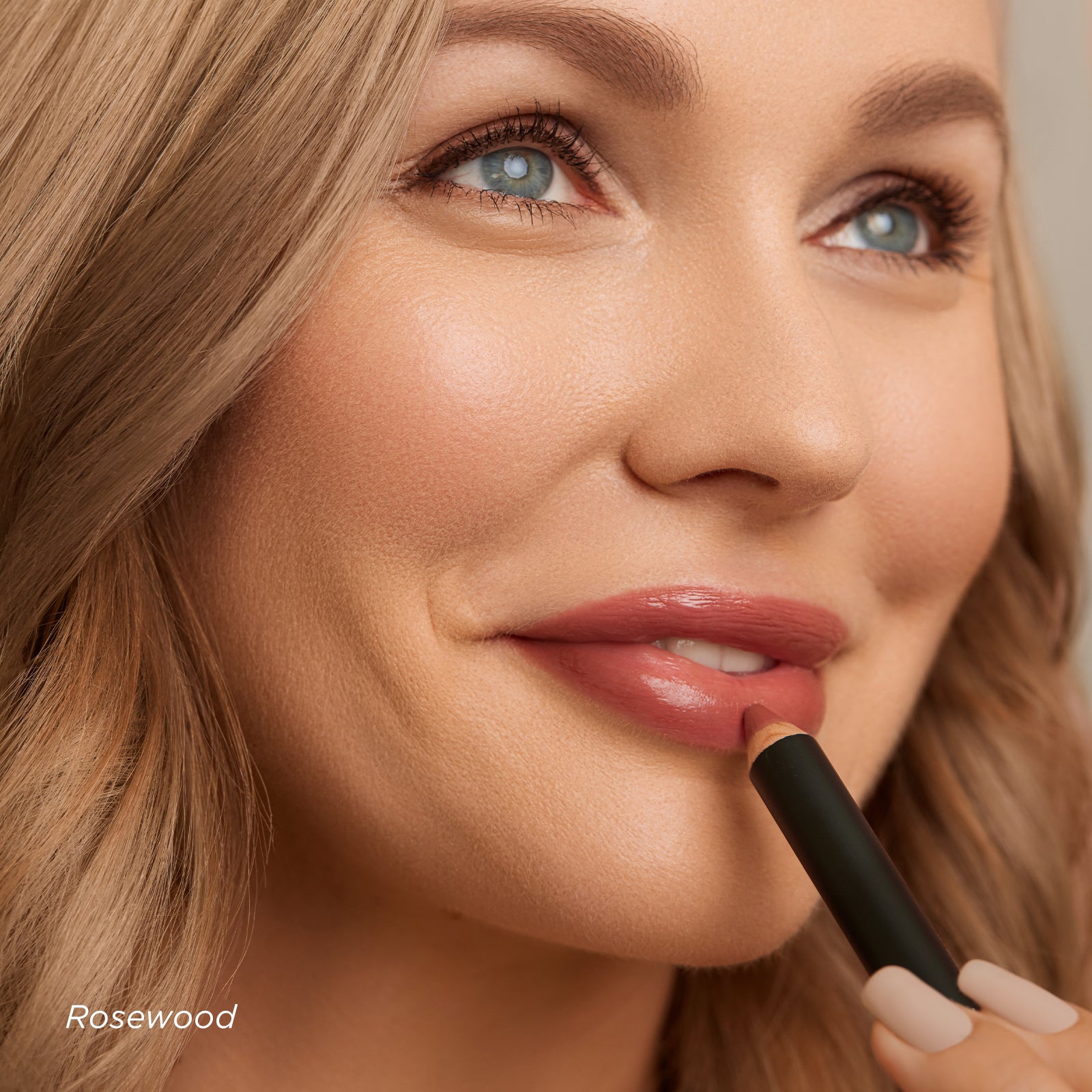 Woman applying lipstick with a focus on her face and the product.