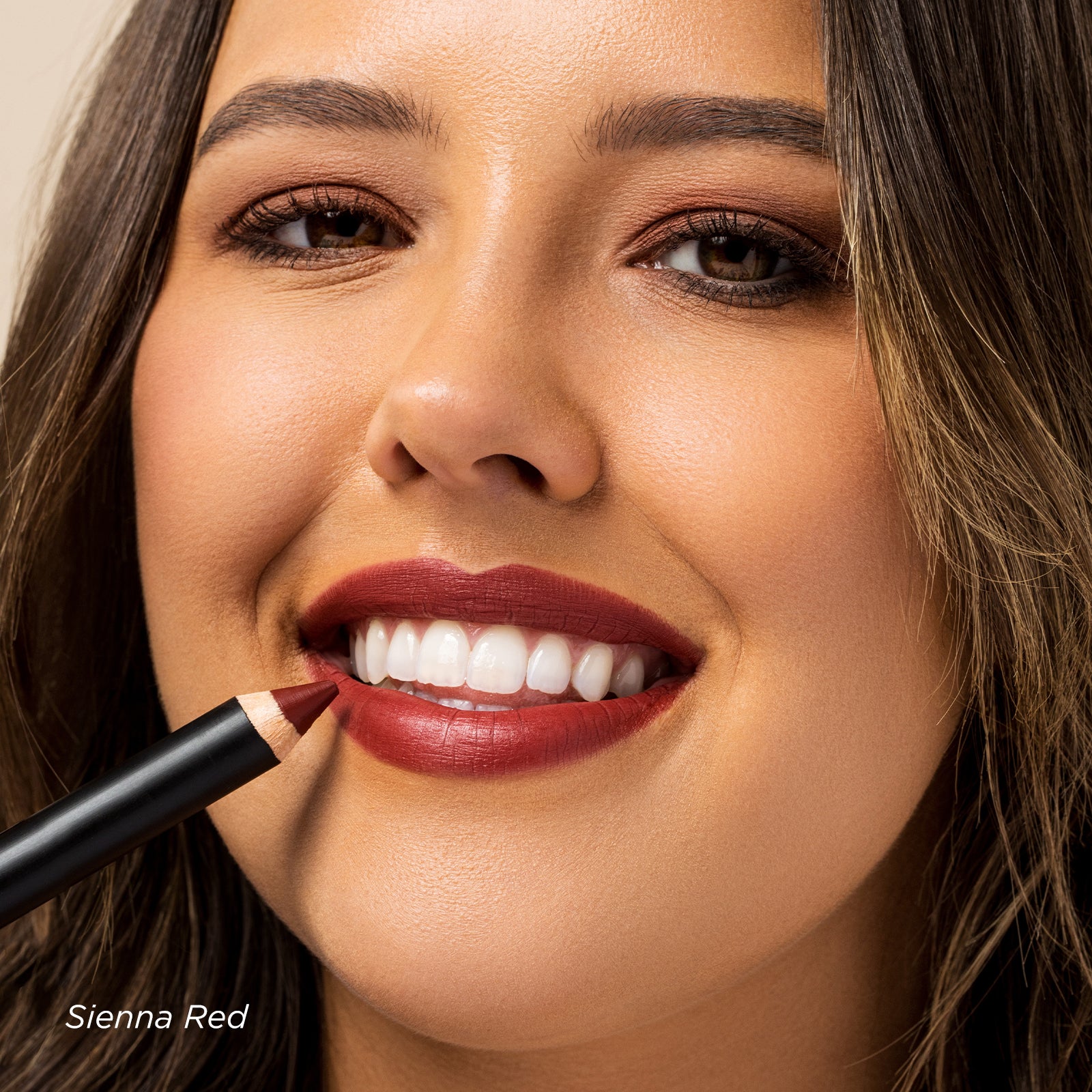 Woman applying lipstick with a focus on her lips and the color 'Sienna Red'.
