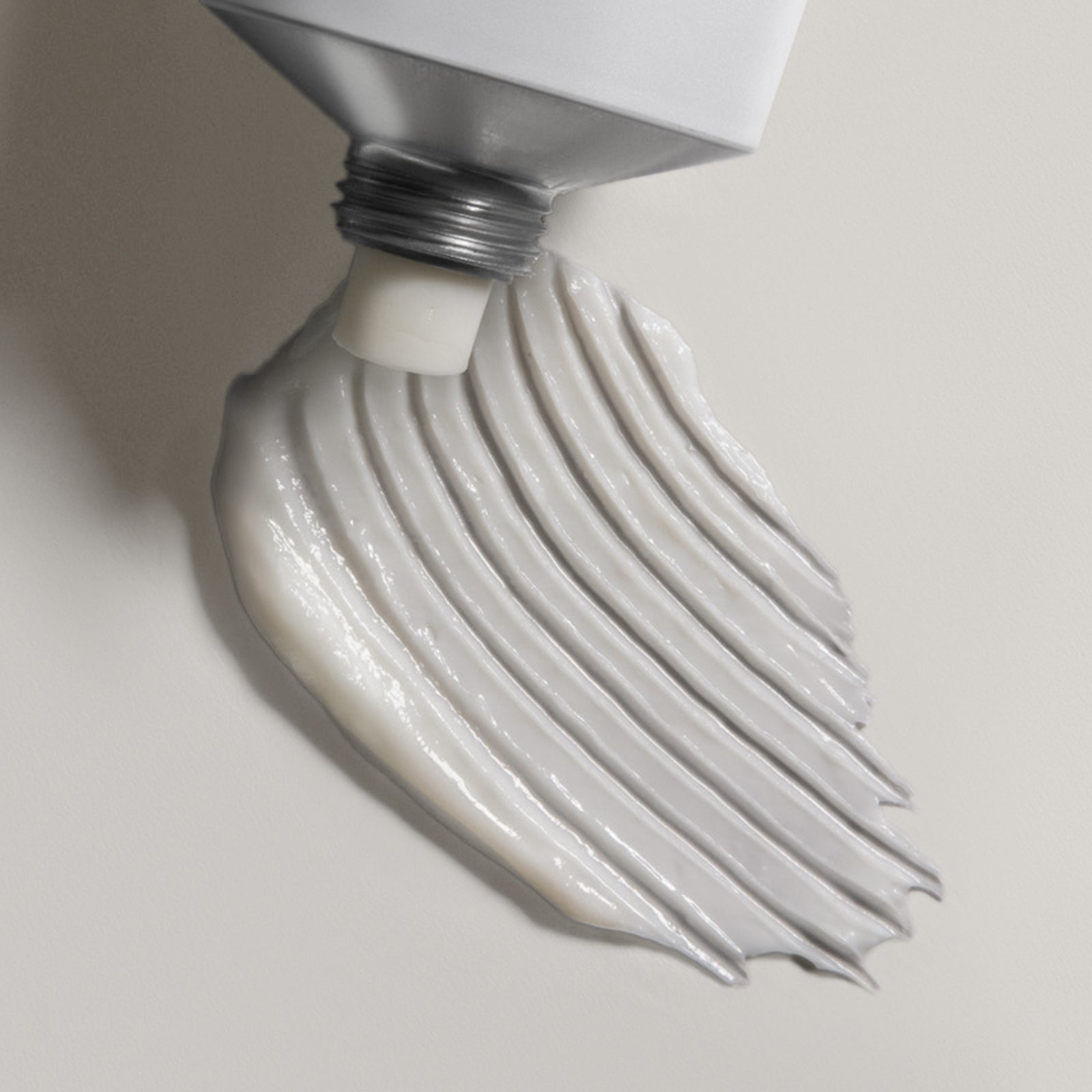 Close-up of a light bulb with a white substance dripping from it on a neutral background
