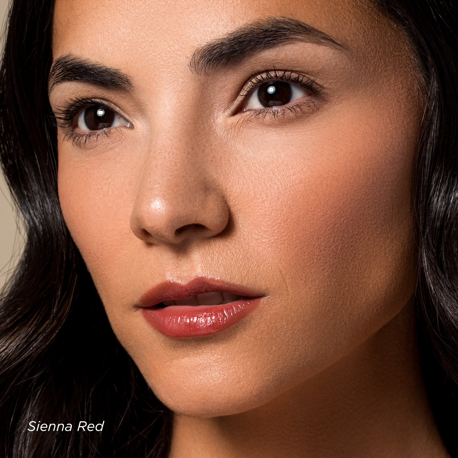 Close-up of a woman's face with dark hair and red lipstick on a neutral background