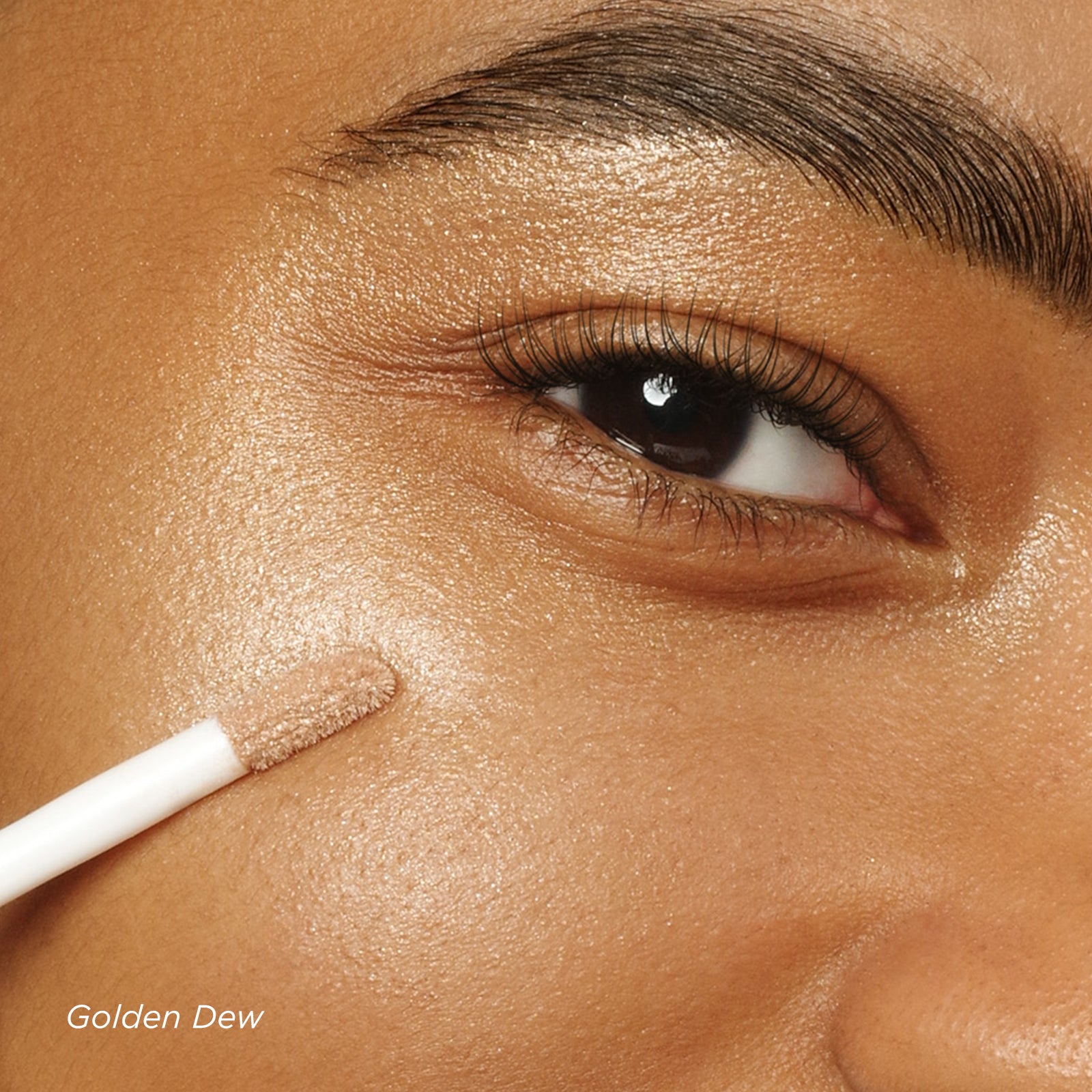 Close-up of a person applying 'Golden Dew' makeup to their face with a brush.